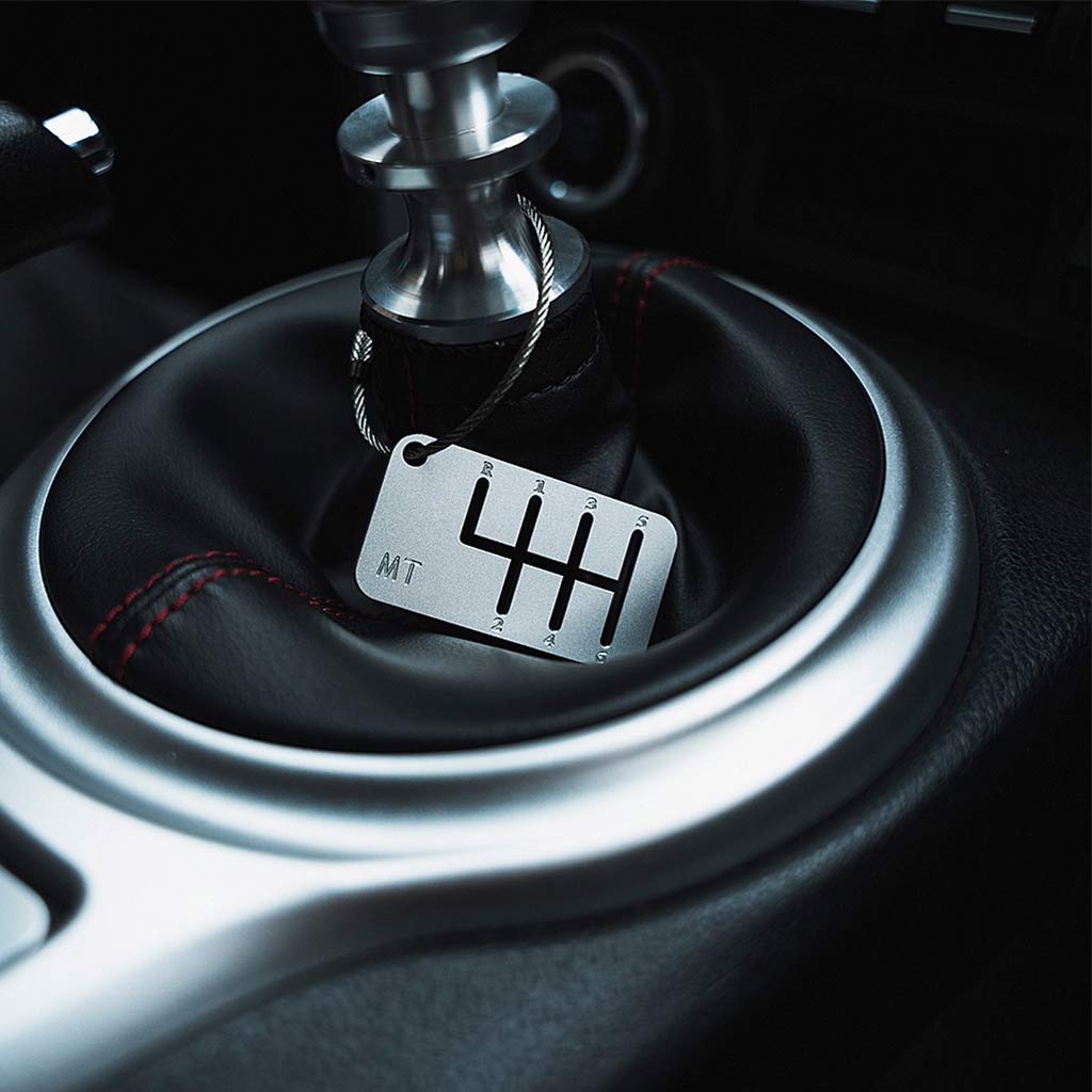 A six-speed manual shift keychain with matte silver finish hung on a shift boot