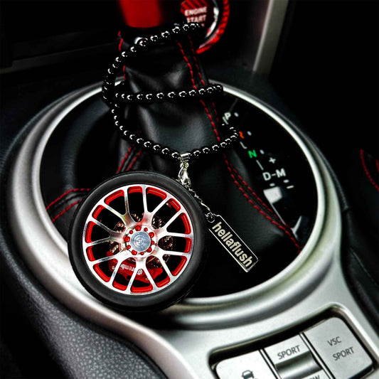 A red BBS wheel air-freshener with its beads twining around an auto car's the shift boot