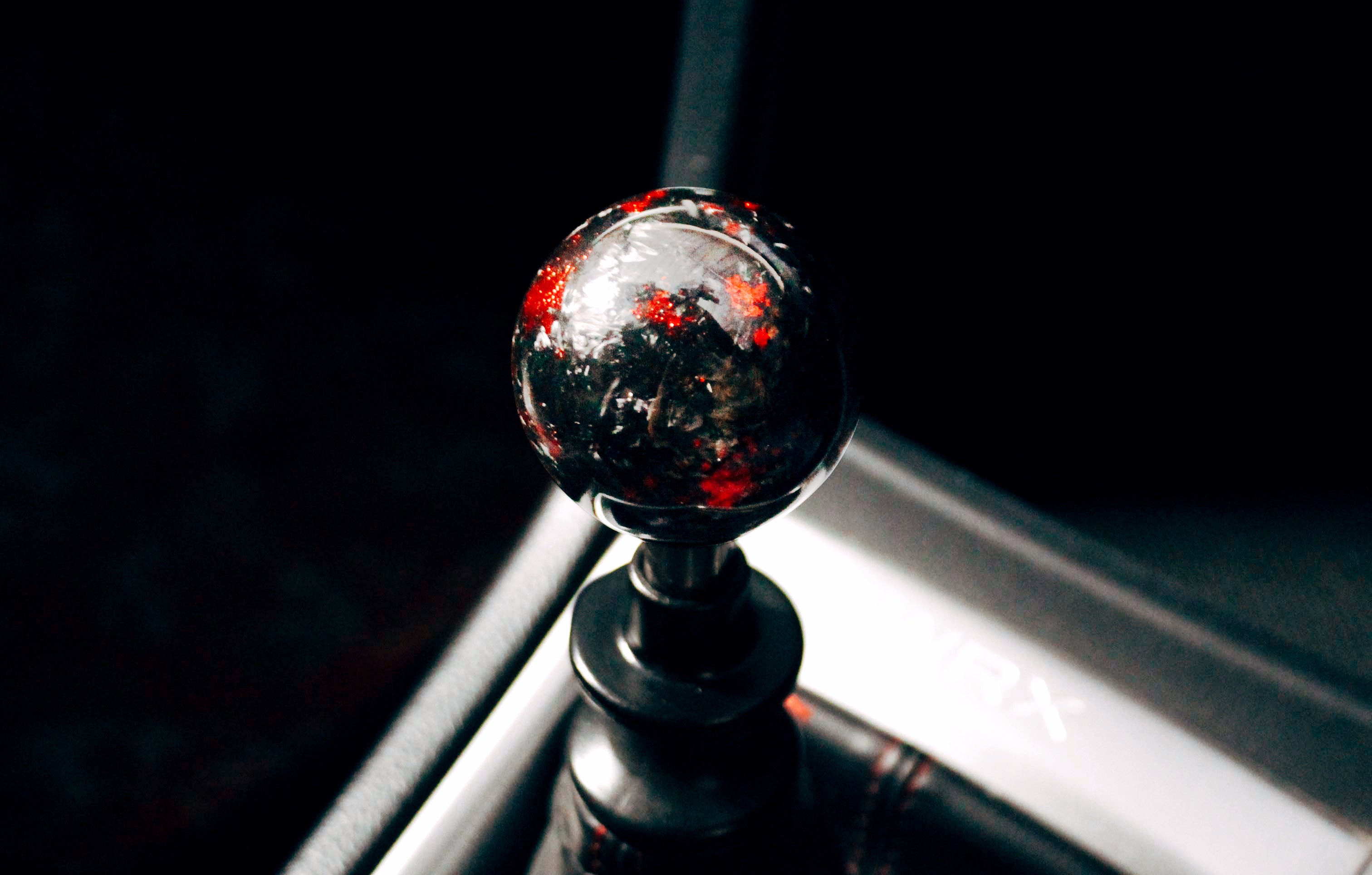 A red and black aftermarket shift knob installed on a 2015 manual Subaru WRX