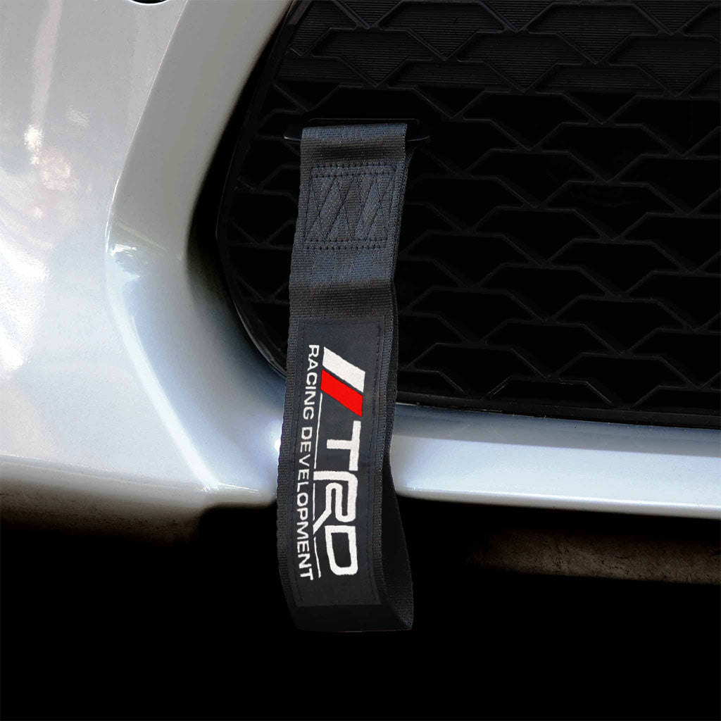 A black TRD tow strap installed on a Toyota 86's front grill