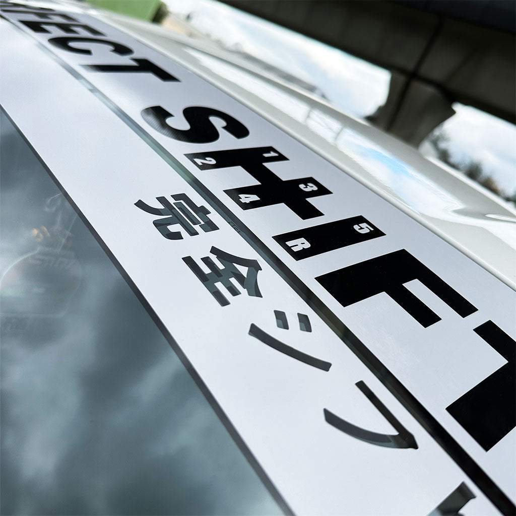 A branded Perfect Shift windshield banner with grey background applied on a Toyota 86 under a bridge