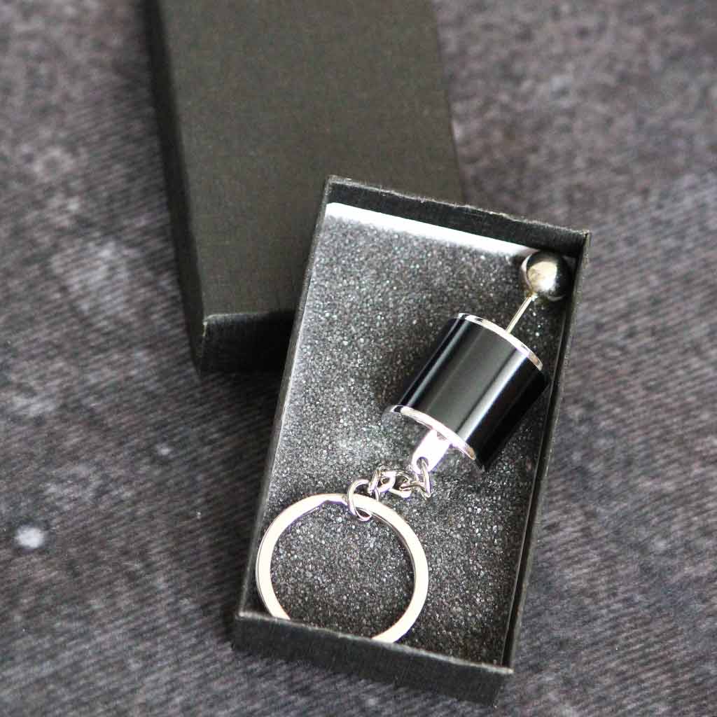 A black turbo keychain in a black gift box on a grey fabric as background