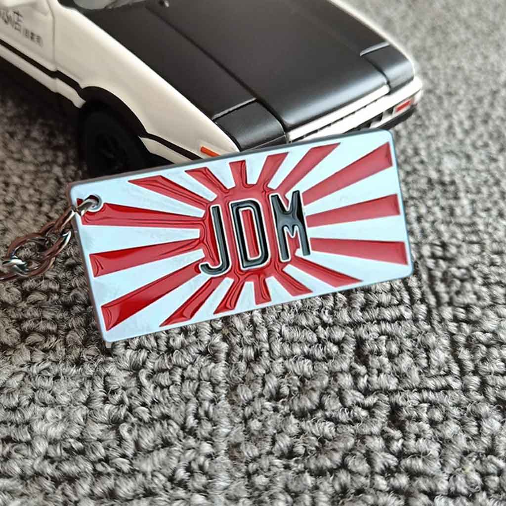 A JDM keychain placed in front of an AE86 car model on carpet