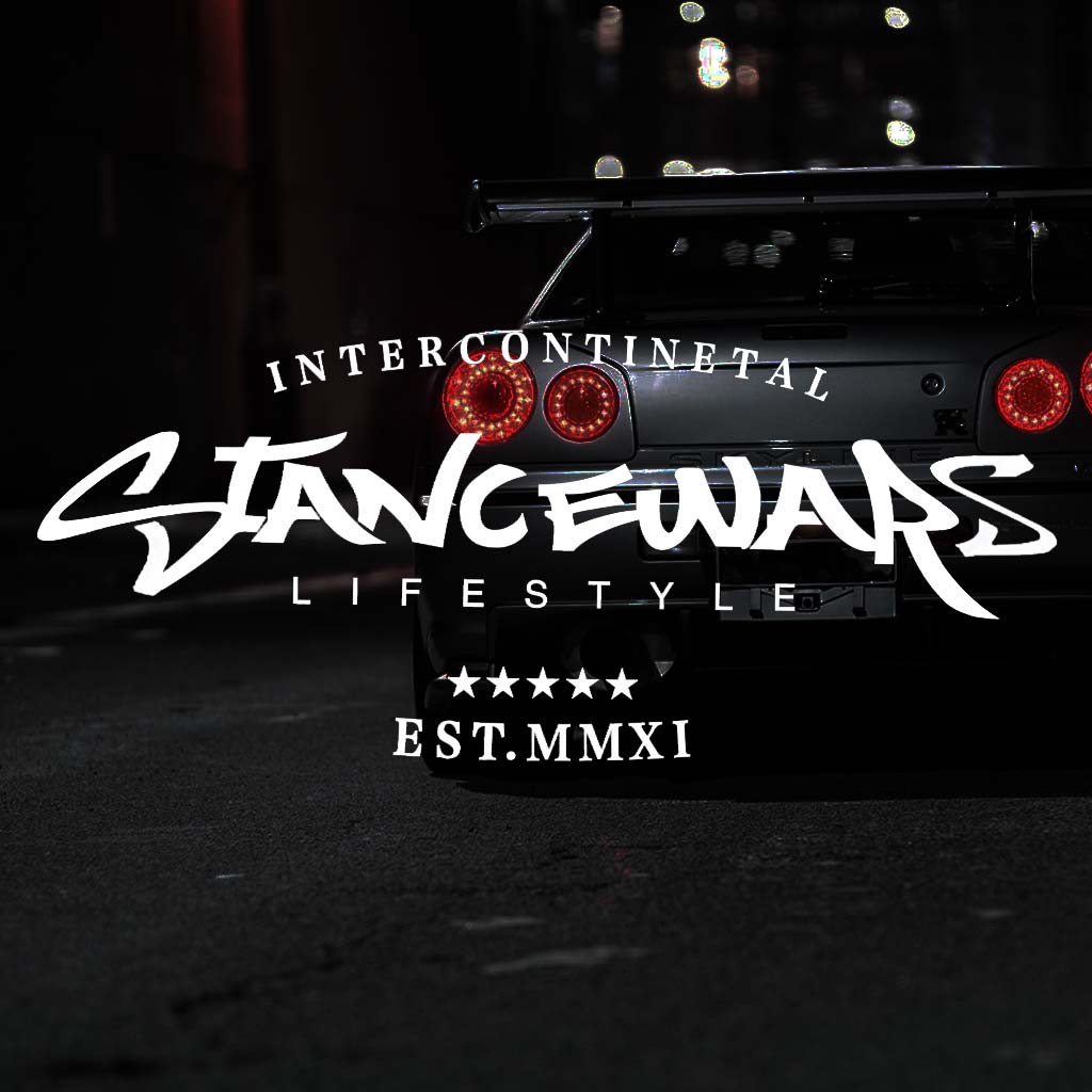 A white stance wars car vinyl decal horizontally placed pointing to the screen with a darkened Skyline R34 at the back