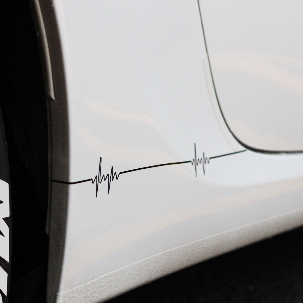 Two black pulse-shaped car vinyl decals applied on a white car's side skirt