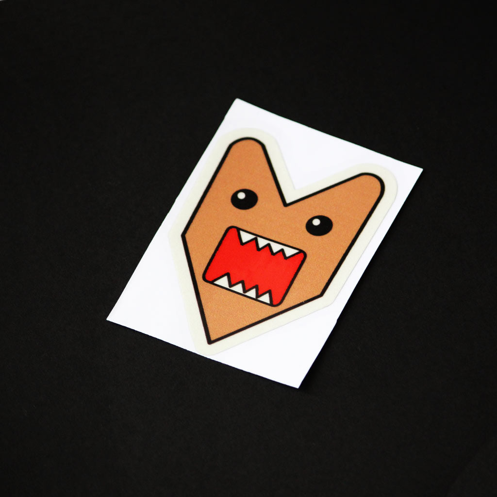 A Domo Kun JDM sticker on a black background in a different position