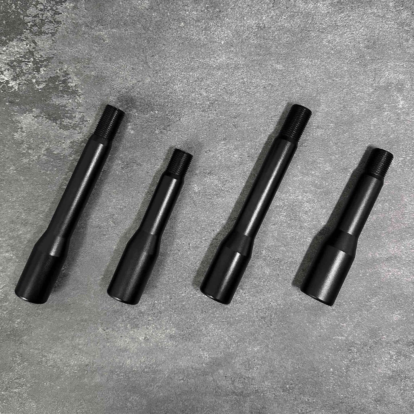 Four shift knob extensions in two different sizes are placed neatly on a grey background