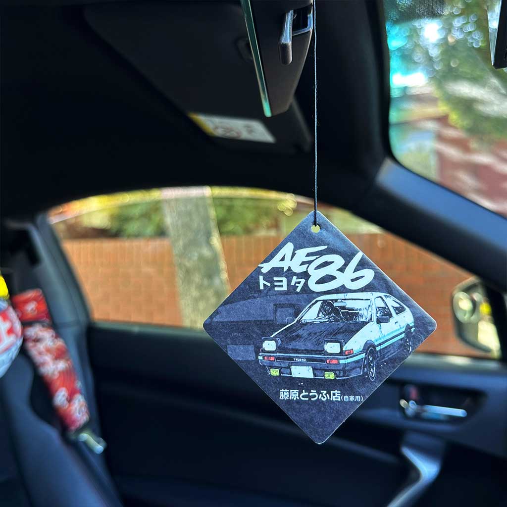 A rear mirror air-freshener themed AE86 and Fujiwara Tofu Shop in a car with the car's interior as a background