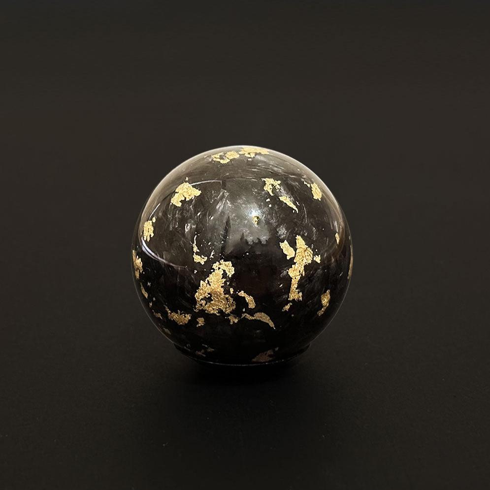 A black spherical carbon fibre shift knob stand on a black background