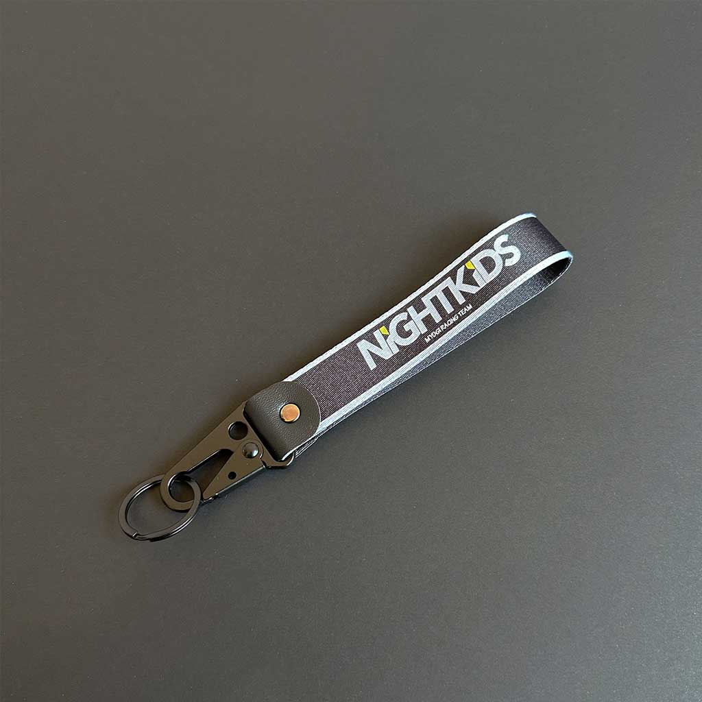 An Initial-D nightkids-themed keychain flat laid on a black background