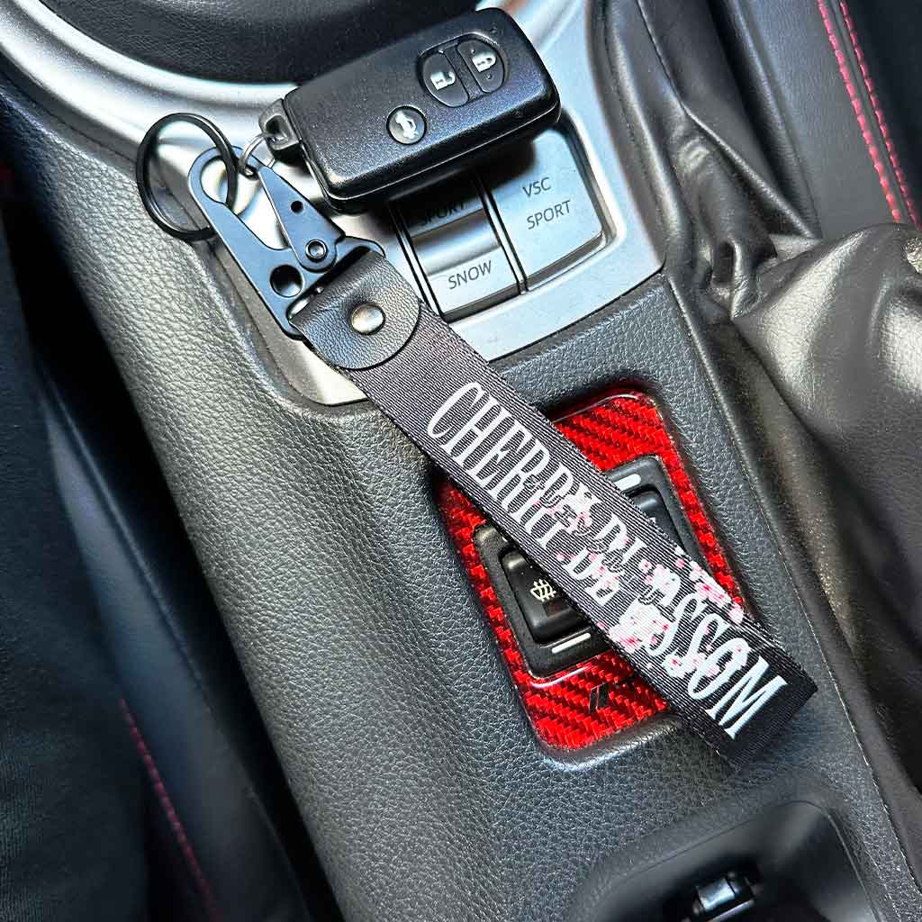 A cherry blossom keychain placed in a Toyota 86's center console