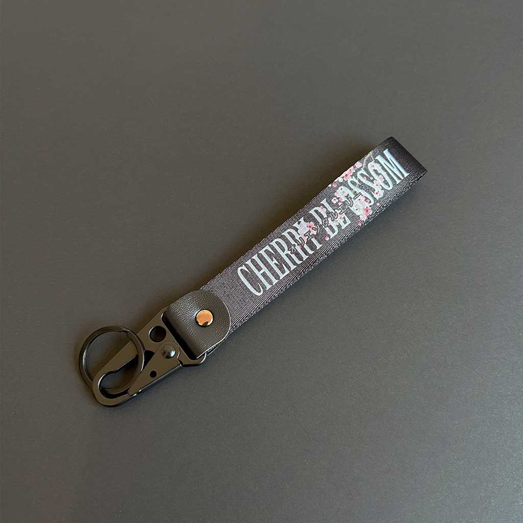 A cherry blossom keychain flat laid on a black background