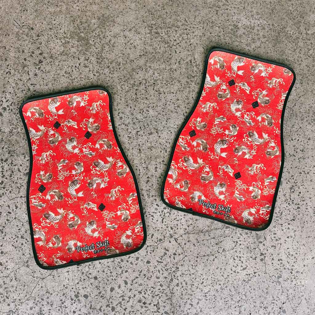Two pieces of red koi fish JDM floor mat flat laid on a garage ground