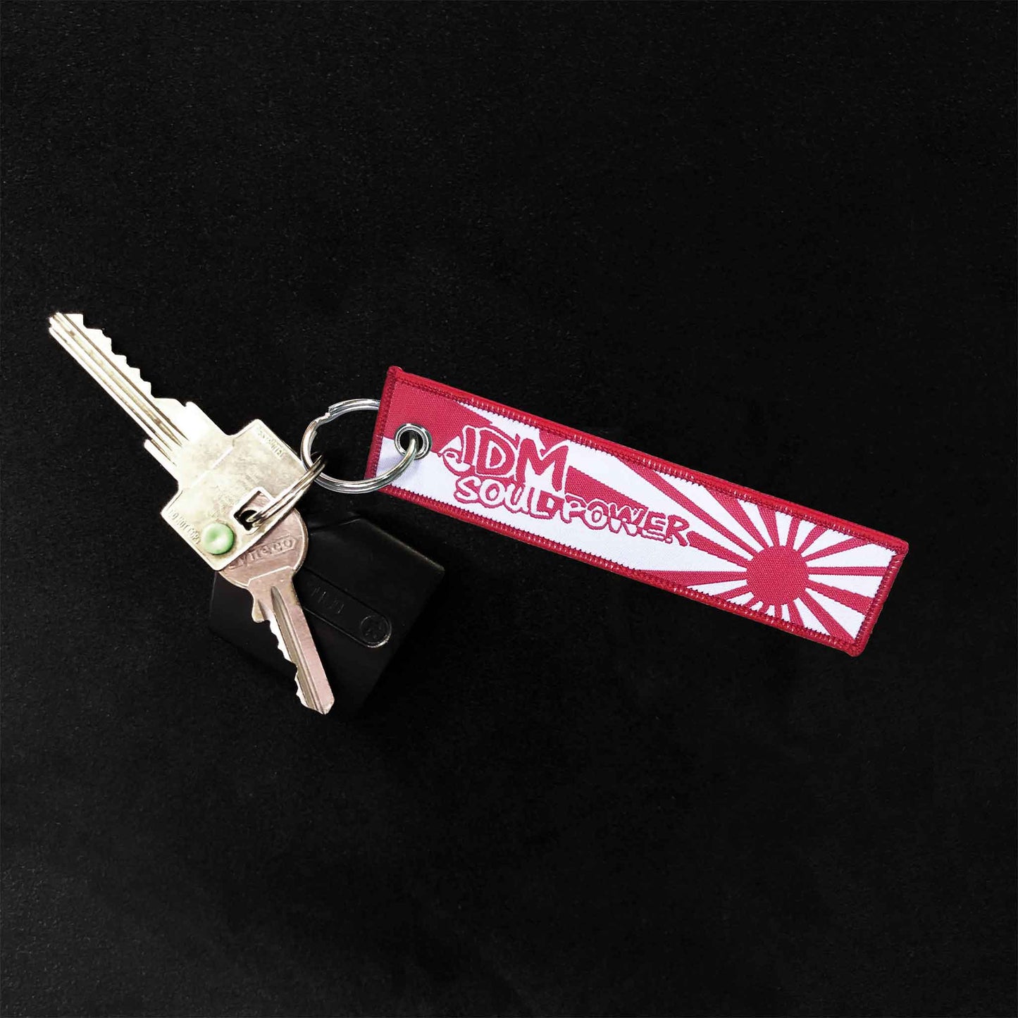A jet tag holding two door keys on a black background