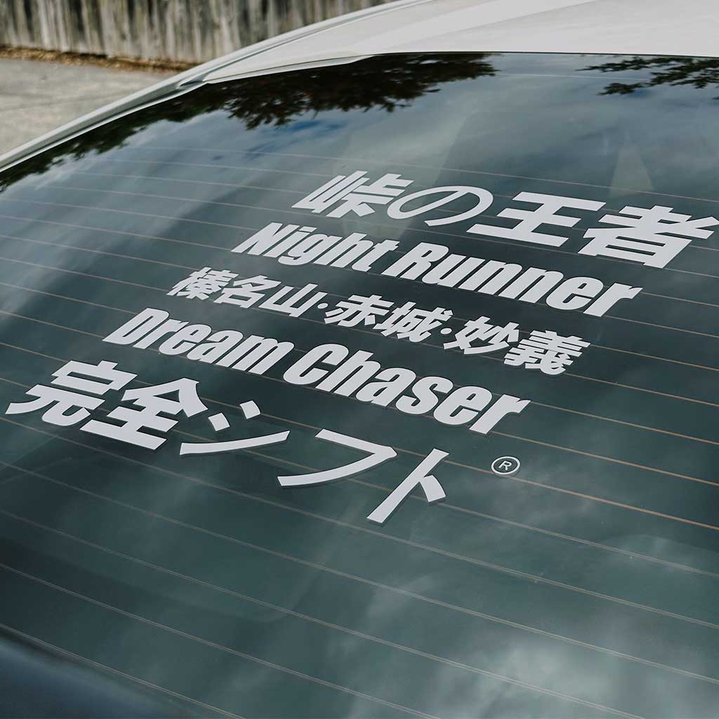 A jdm window decal with English and Japanese characters on a white Toyota 86