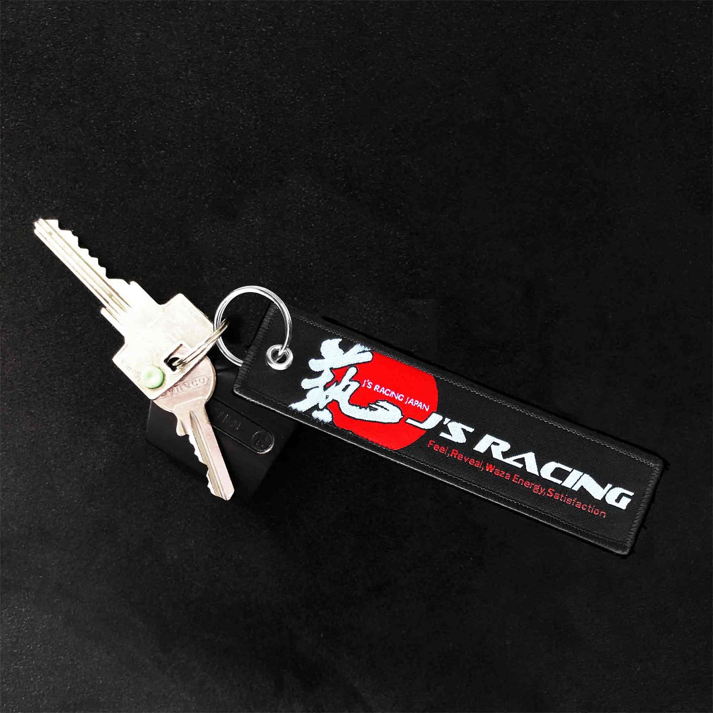 A J's racing jet tag with a red sun and a Japanese writing on a black background