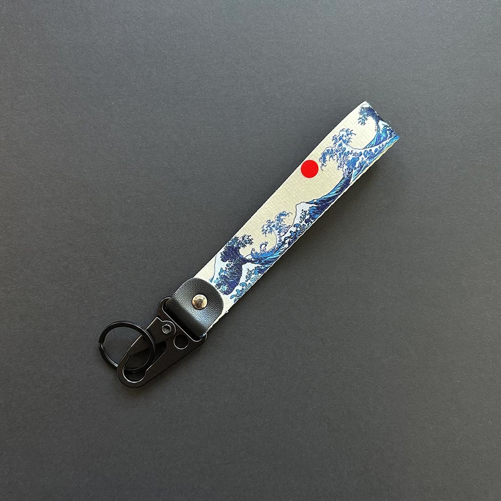 A flat lay great wave lanyard on a black background