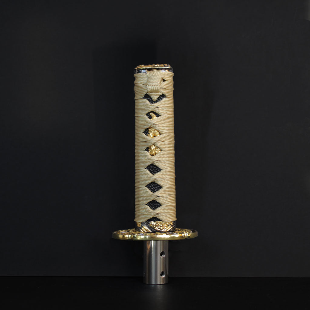 A gold Katana shift knob standing in front of a black wall