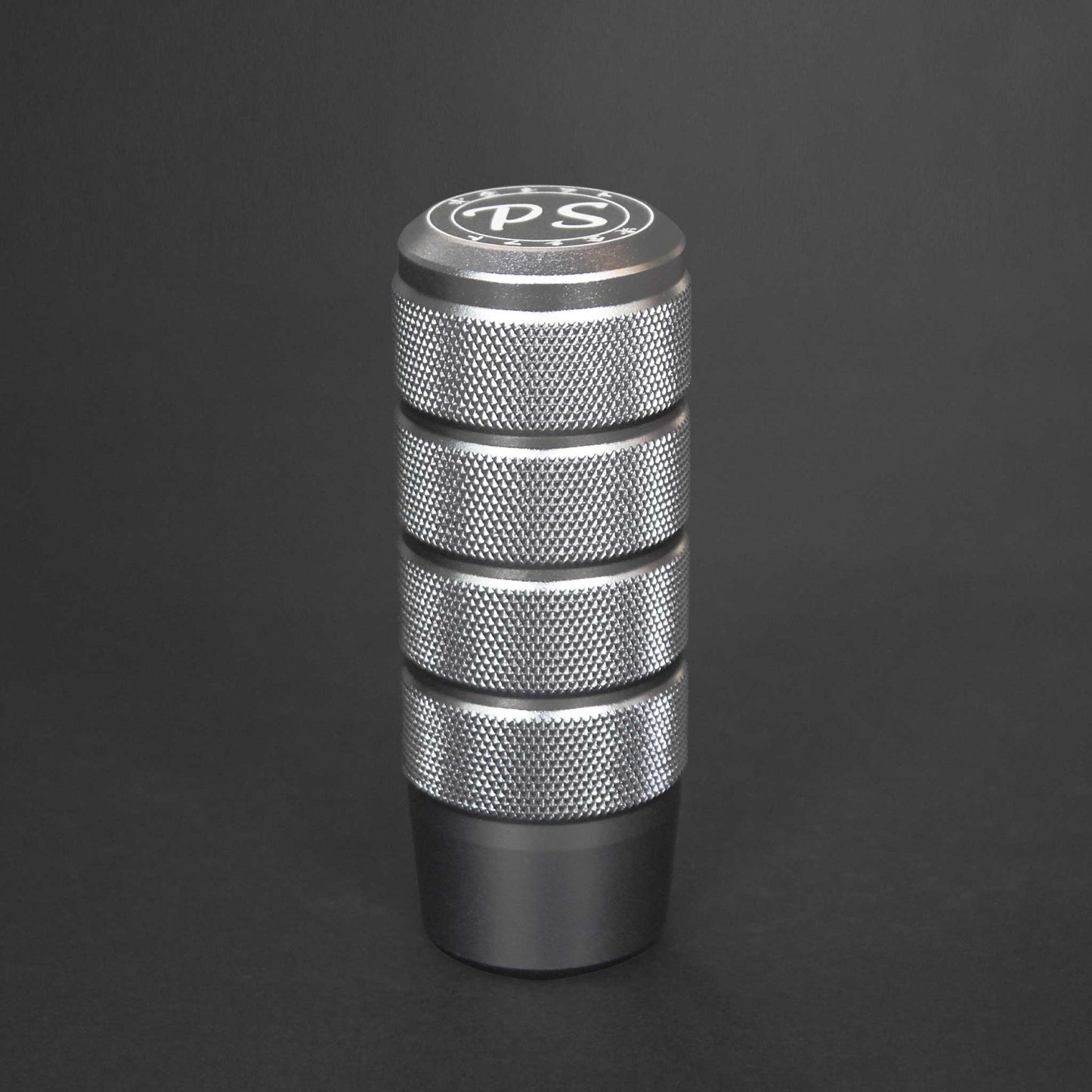 A silver shift knob standing on a black background
