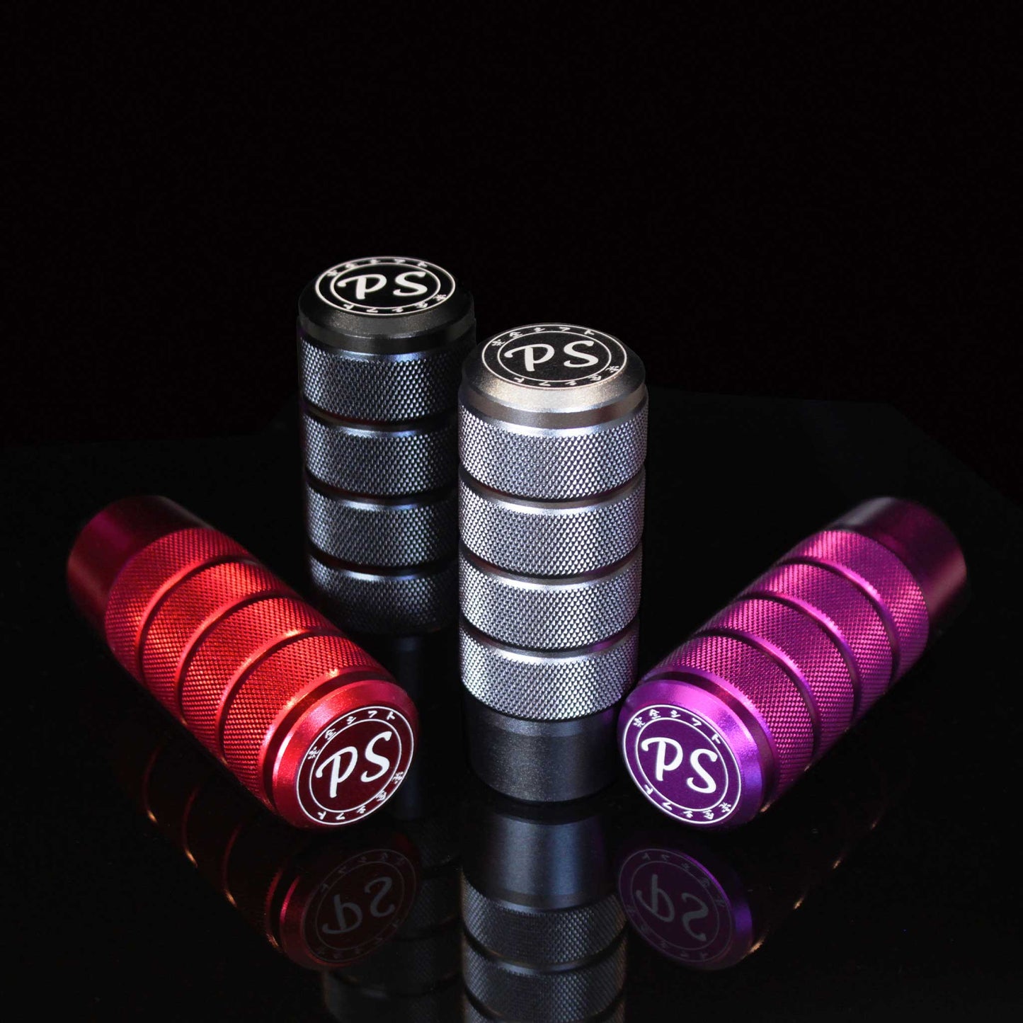 Four shift knobs in different colours aesthetically stand on a mirror