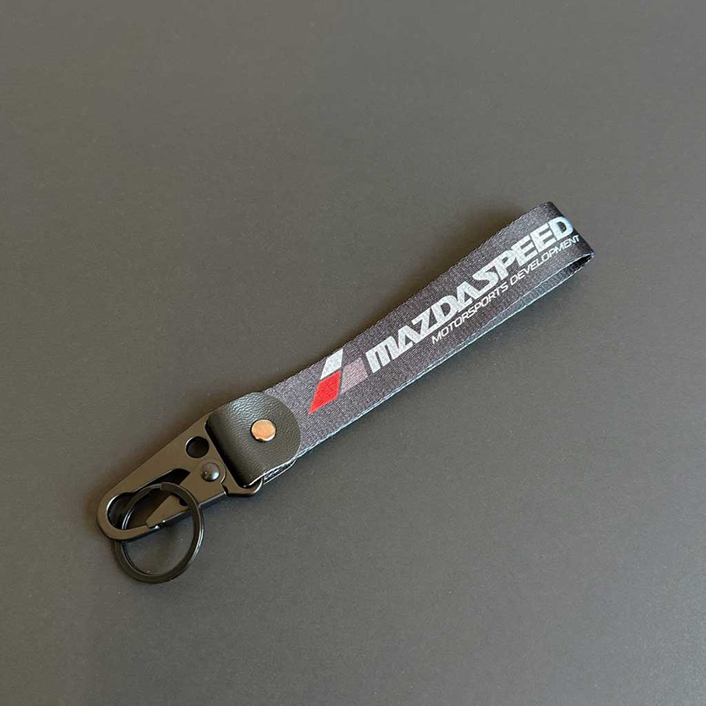 A Mazda lanyard with 'Mazda Speed' characters flat laid on a black background