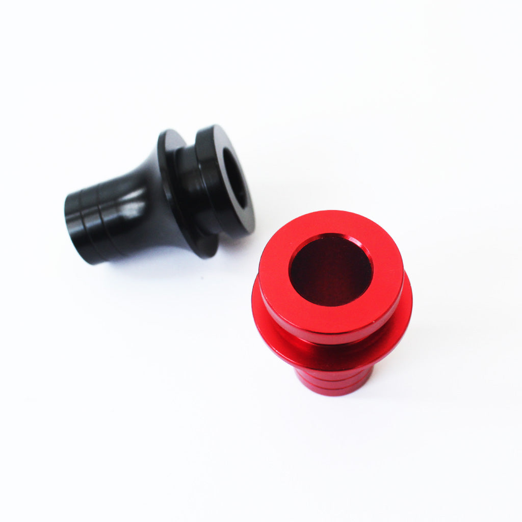 A threaded red boot retainer is standing upright with its bottom non-threaded section pointing towards the screen, and a black boot retainer is flat laid on a white background