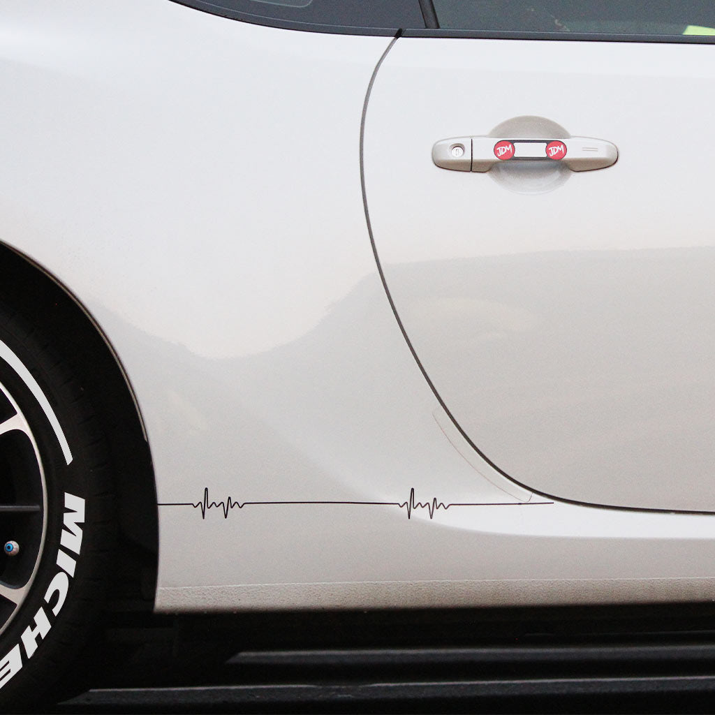 Two black pulse-shaped car vinyl decals applied on a white car's side skirt, the car's tyres are stuck with white letter stickers