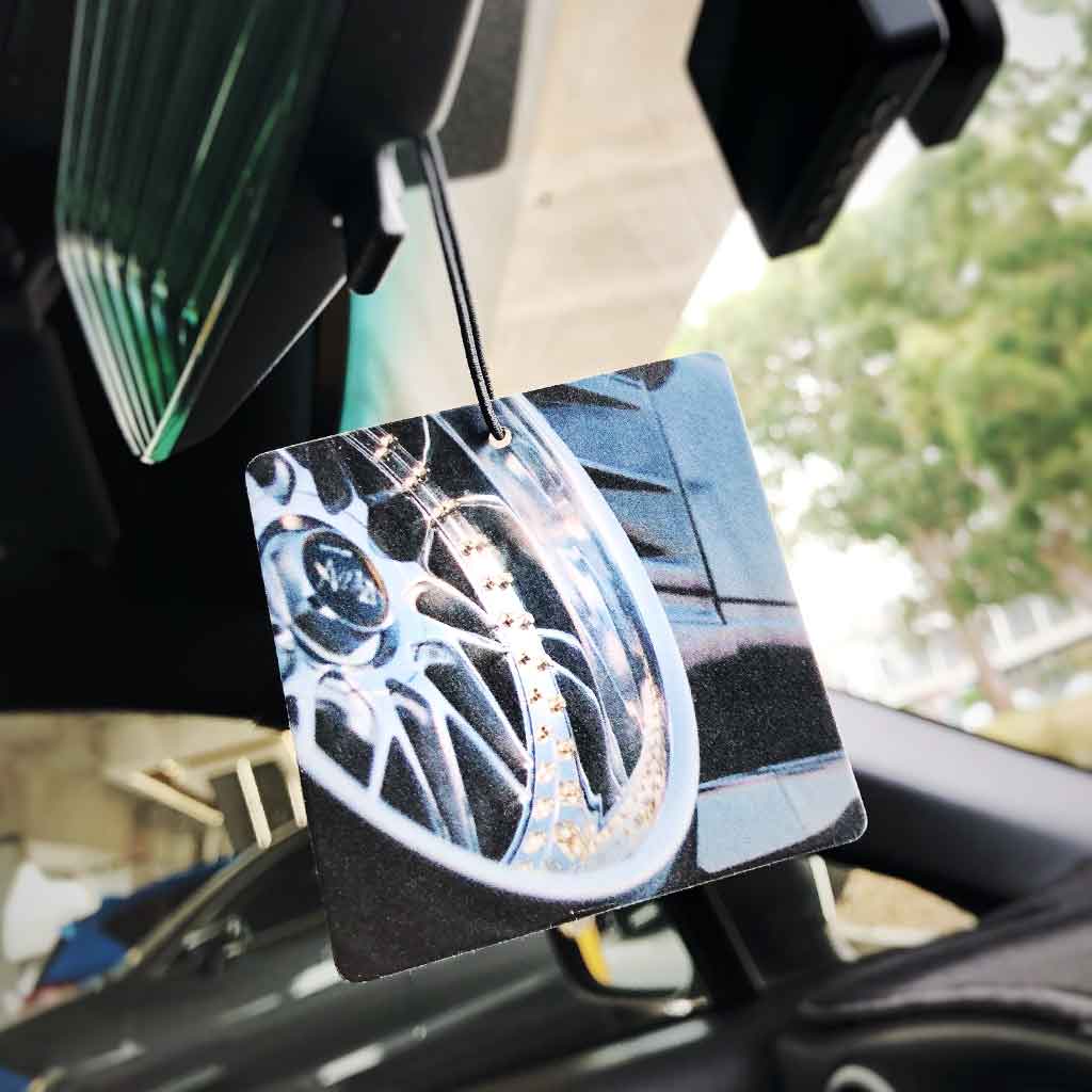 An air freshener featuring a gloss vintage wheel hung in a car