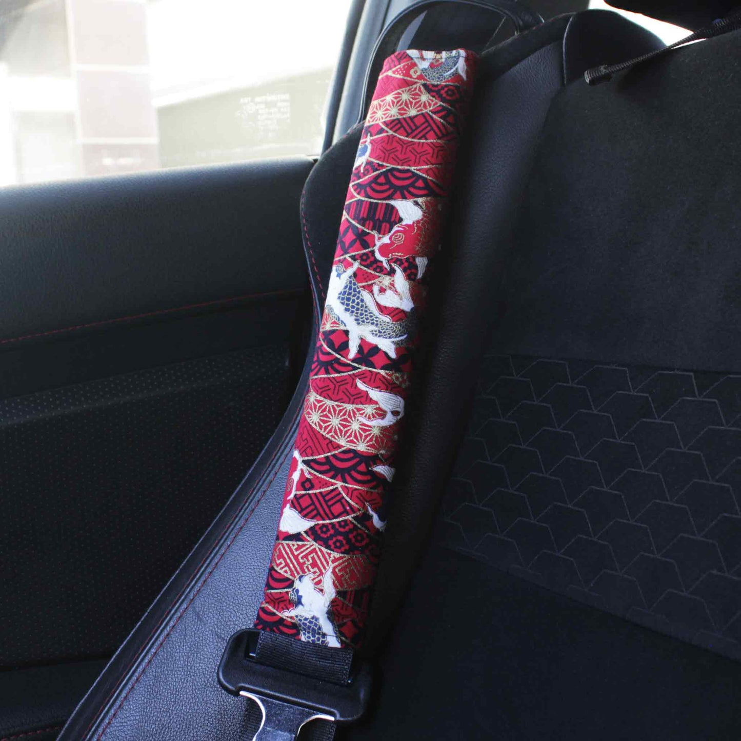 A seat belt cover with red koi fish pattern installed on a Toyota 86's seat belt