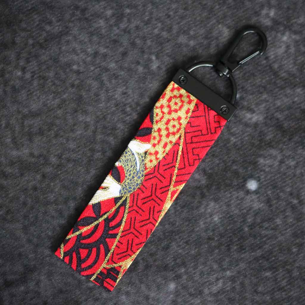 A red koi fish wafu keychain on a grey background