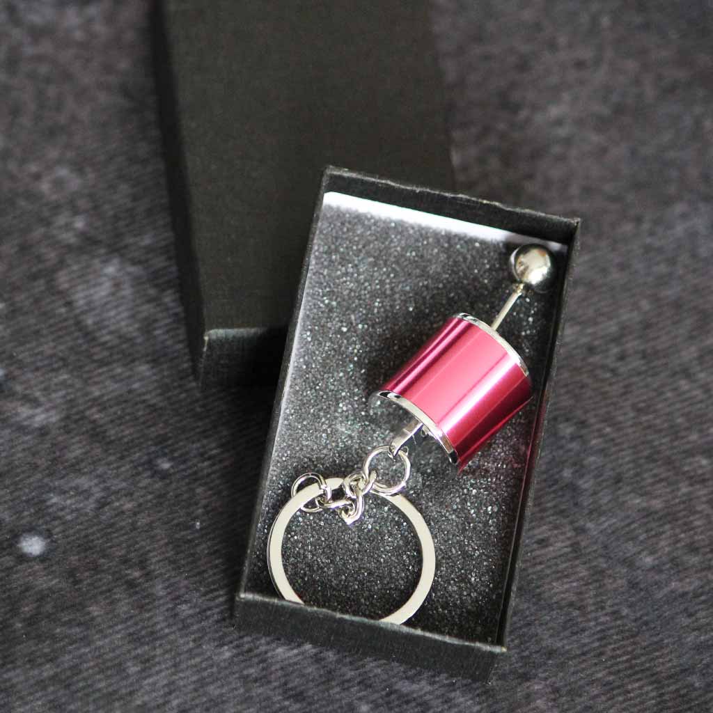 A red turbo keychain in a black gift box on a grey fabric as background