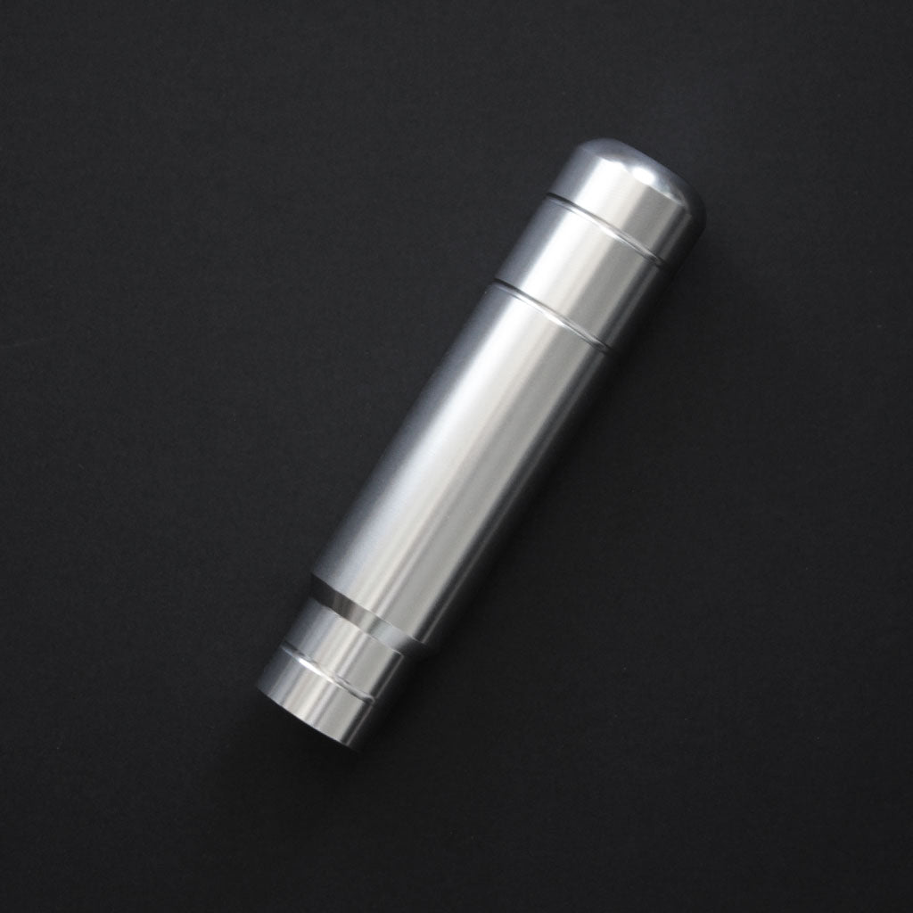 A silver aftermarket shift knob flat laid on a black background