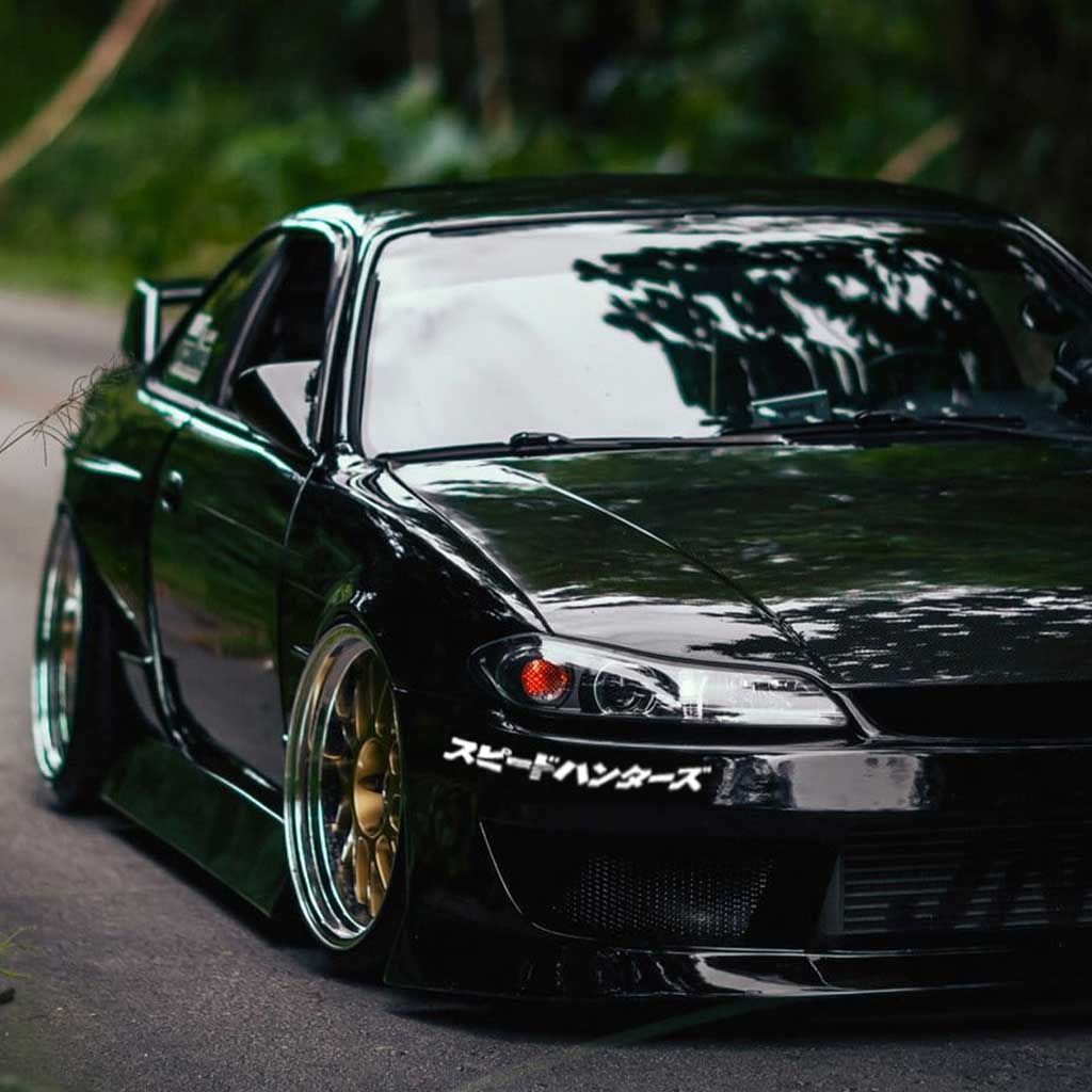 A white Speed Hunters in Japanese car vinyl applied on a black silvia's front bumper