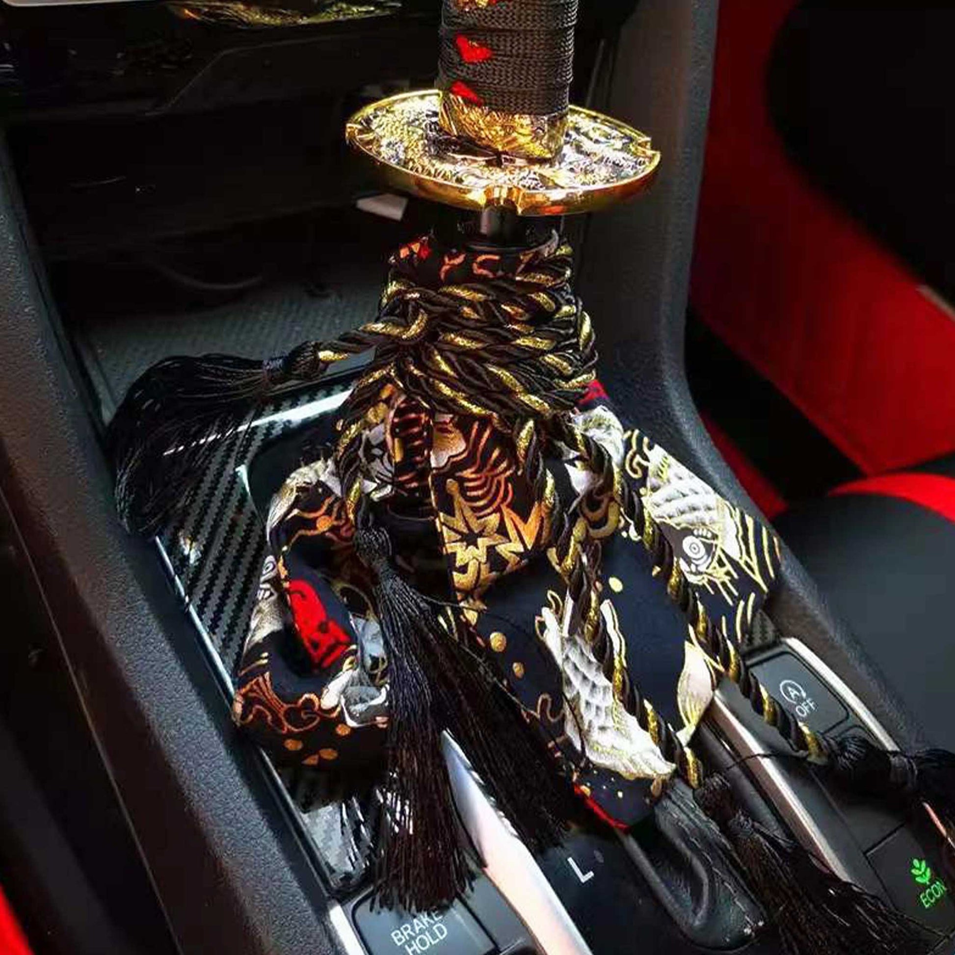A black koi fish shift stick cover installed on a car's shift boot underneath a black katana sword shift knob