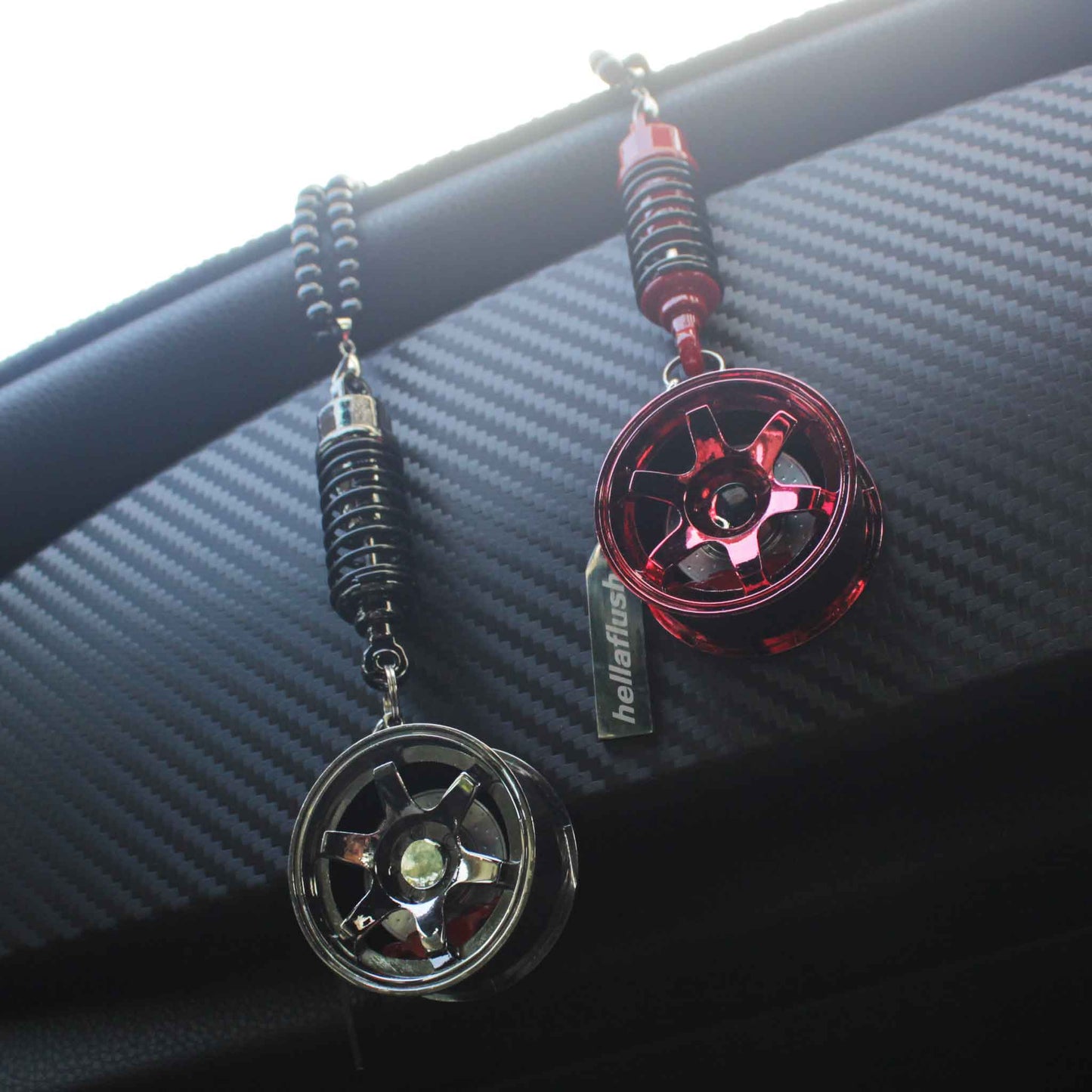 Two wheel decors hung on a car's carbon fibre centre console, one is black and one is red