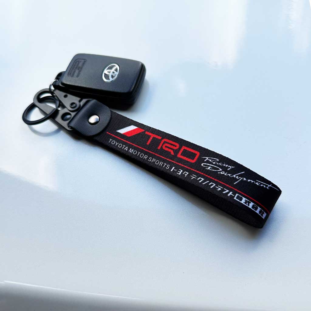 A Toyota TRD keychain flat laid on a white 86's hood