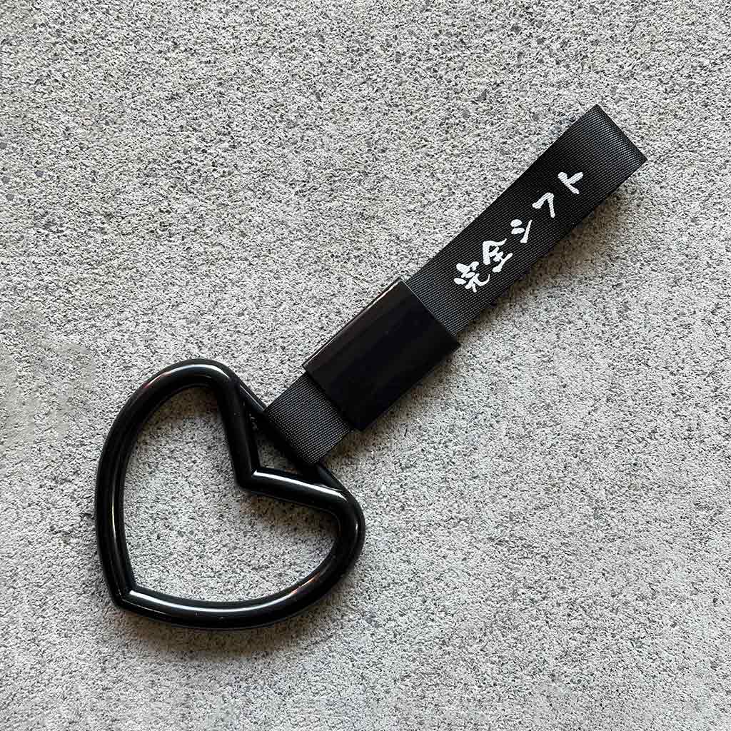 A black heart Tsurikawa with black strap placed on a concrete ground