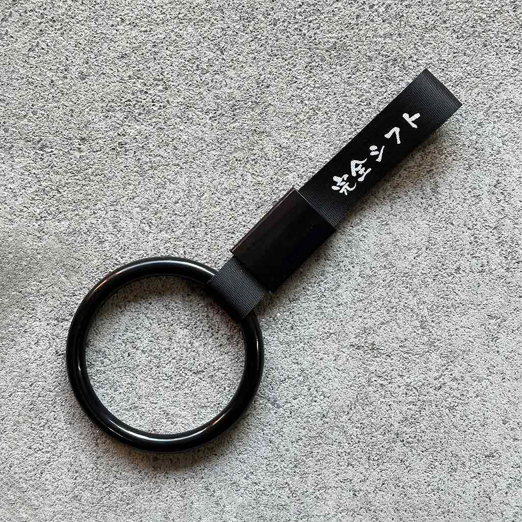 A black ring Tsurikawa with black strap placed on a concrete ground