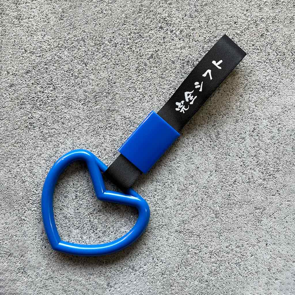A blue heart Tsurikawa with black strap placed on a concrete ground