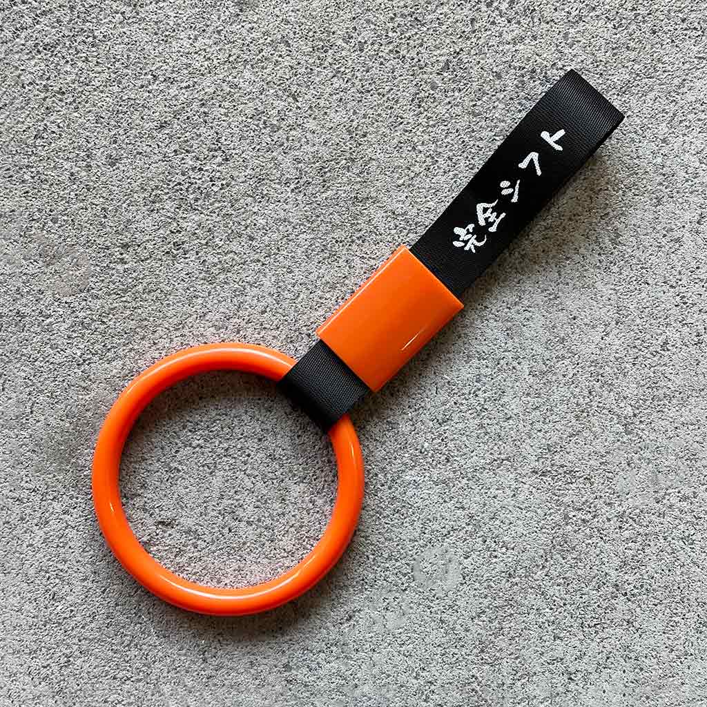 A orange ring Tsurikawa with black strap placed on a concrete ground