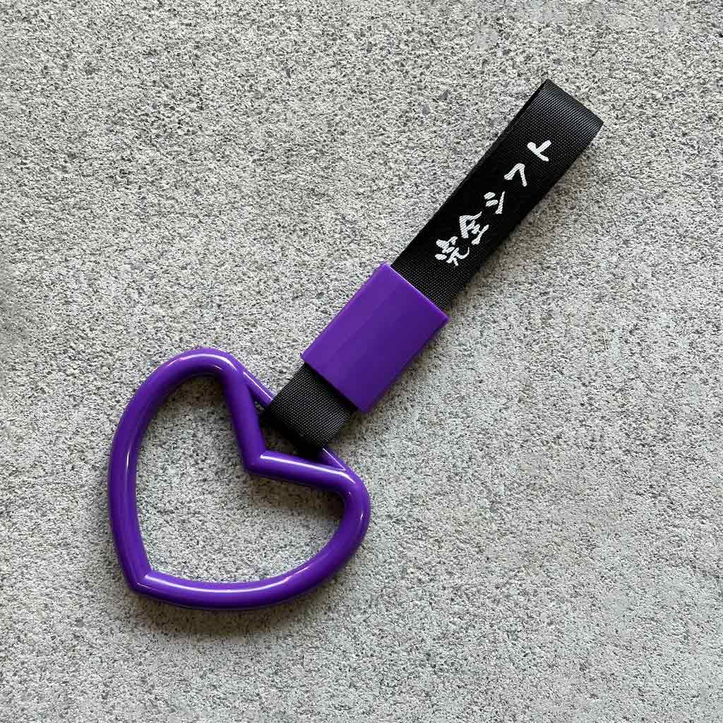 A purple ring Tsurikawa with black strap placed on a concrete ground