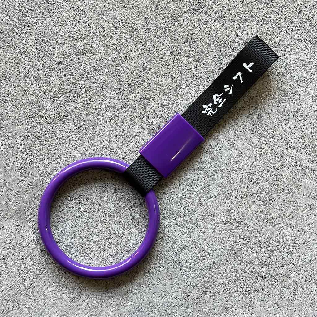 A purple heart Tsurikawa with black strap placed on a concrete ground