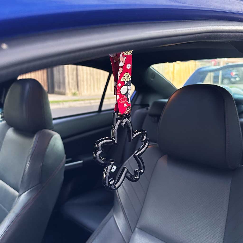 A black sakura Tsurikawas with maneki-shiba strap hung in a car