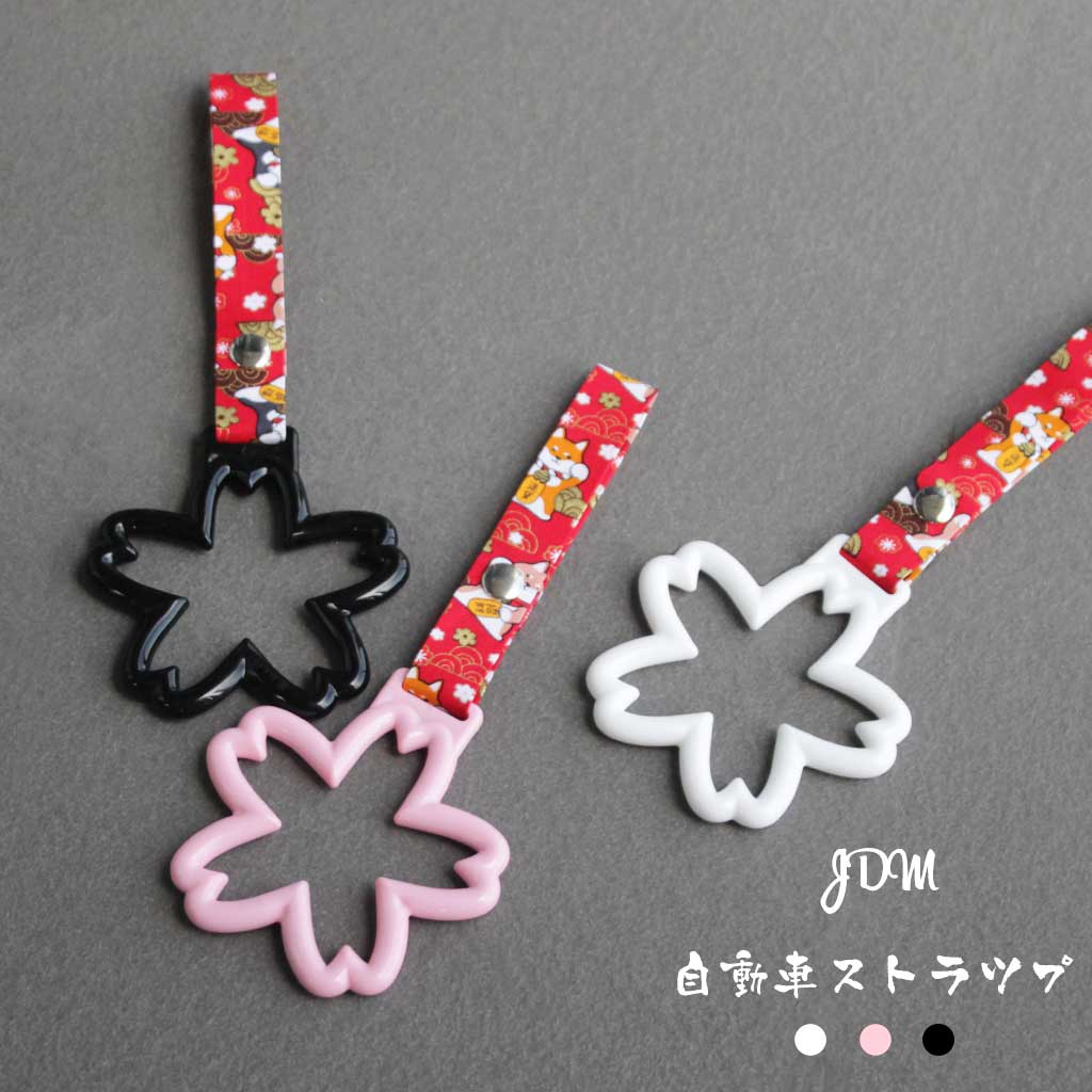 Some sakura Tsurikawas with maneki-shiba strap flat laid on a concrete floor