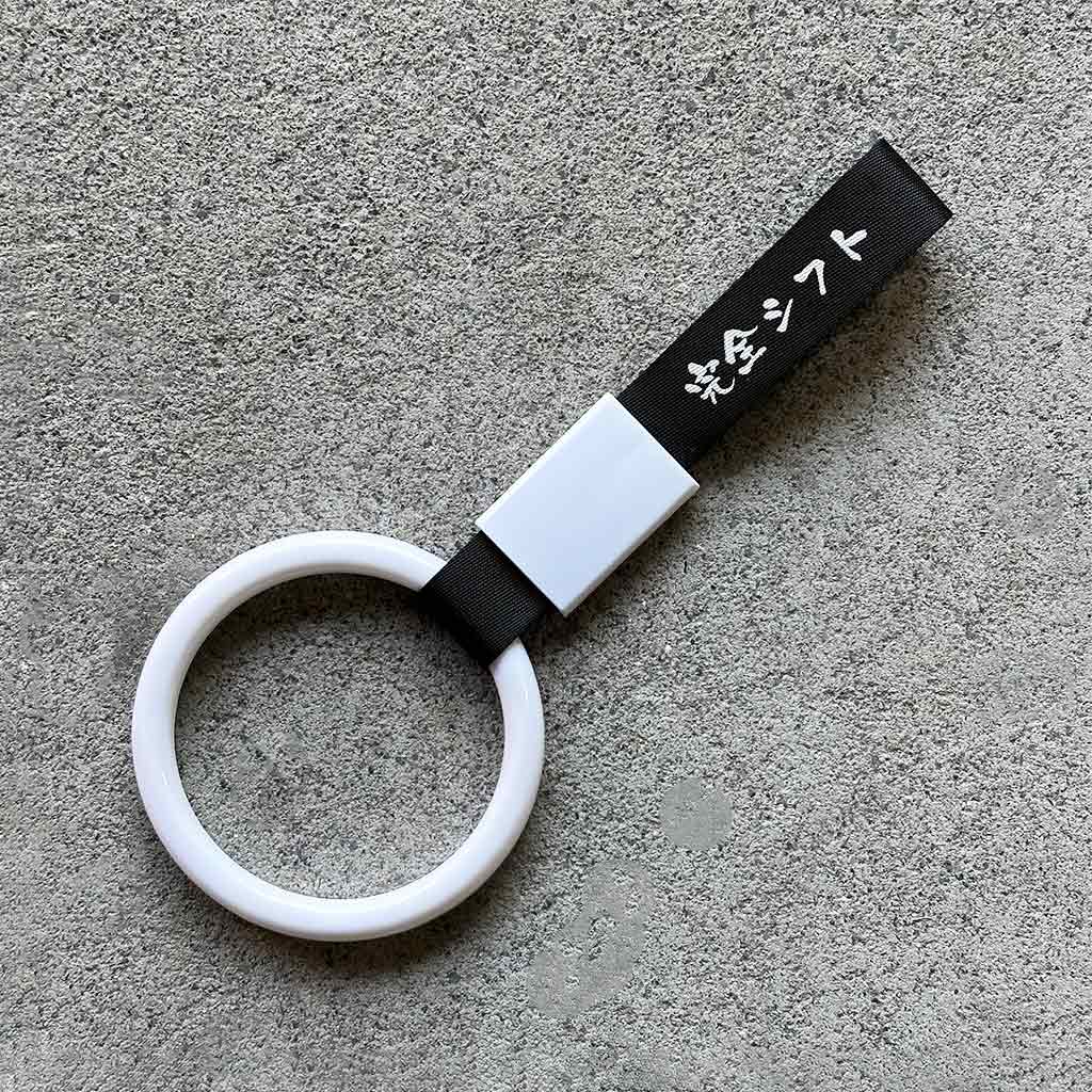 A white ring Tsurikawa with black strap placed on a concrete ground