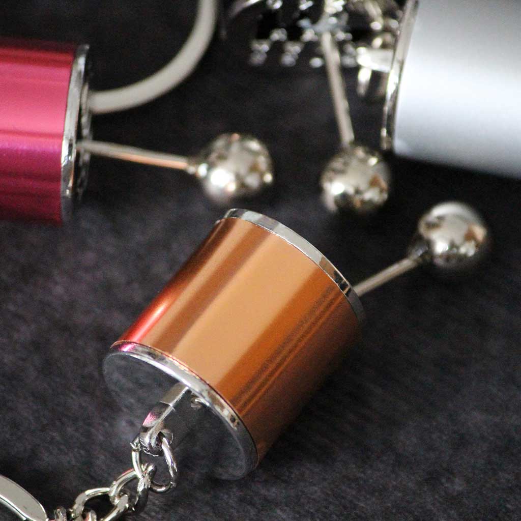 Close-up of a yellow turbo keychain with the red and grey ones on side