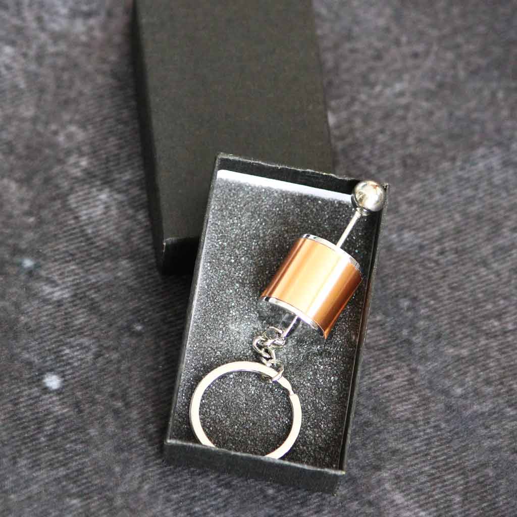 A yellow turbo keychain in a black gift box on a grey fabric as background