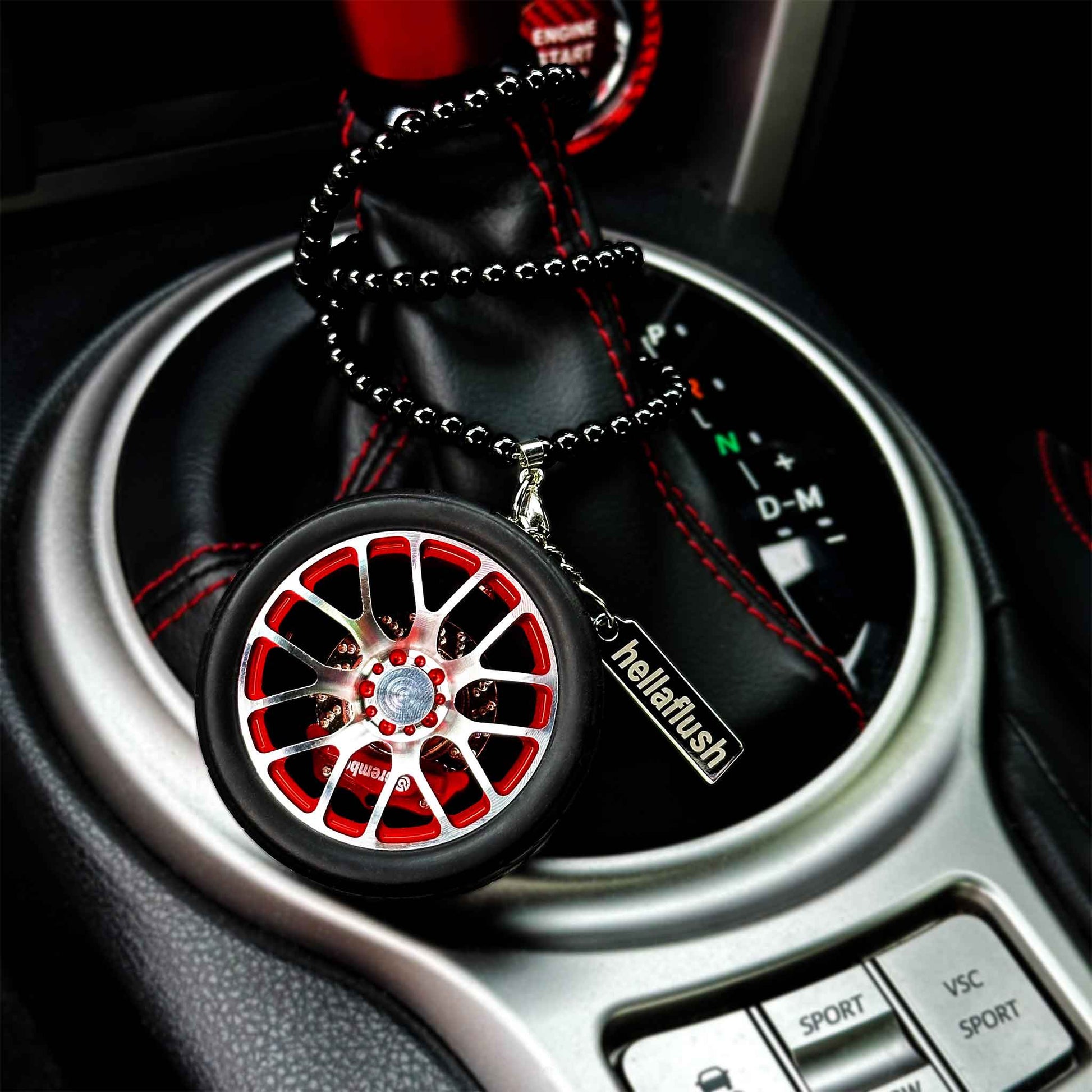 A red BBS wheel air-freshener with its beads twining around an auto car's the shift boot