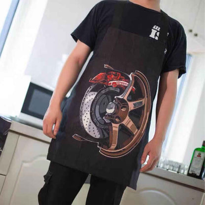 A man wearing a black Volk-wheel-themed apron, standing in the kitchen