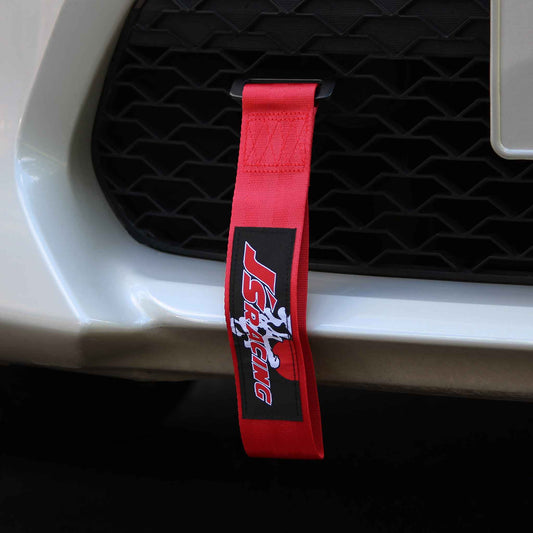 A red js racing tow strap installed on a white car's front grille